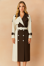 A stylish Australian woman with long ash blond hair wears a modern two-tone trench coat, posed against a softly lit warm sand and pastel pink background, ideal for chic autumn-winter fashion campaigns